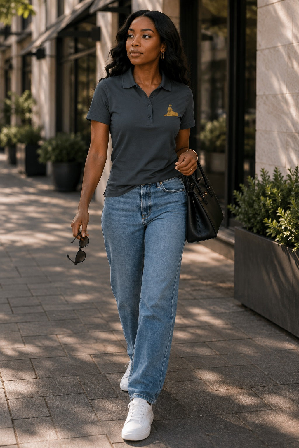Black woman wearing the BLACK MAJIC Women's Crown Polo in Storm Grey, walking, full length