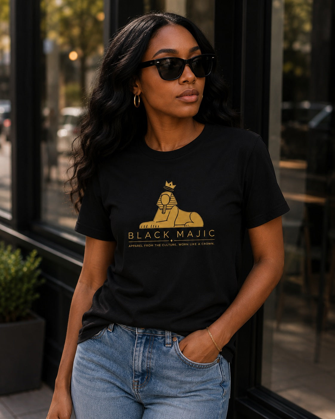 Black woman wearing the BLACK MAJIC Crown Graphic Tee in black, filled gold crowned Sphinx over the wordmark
