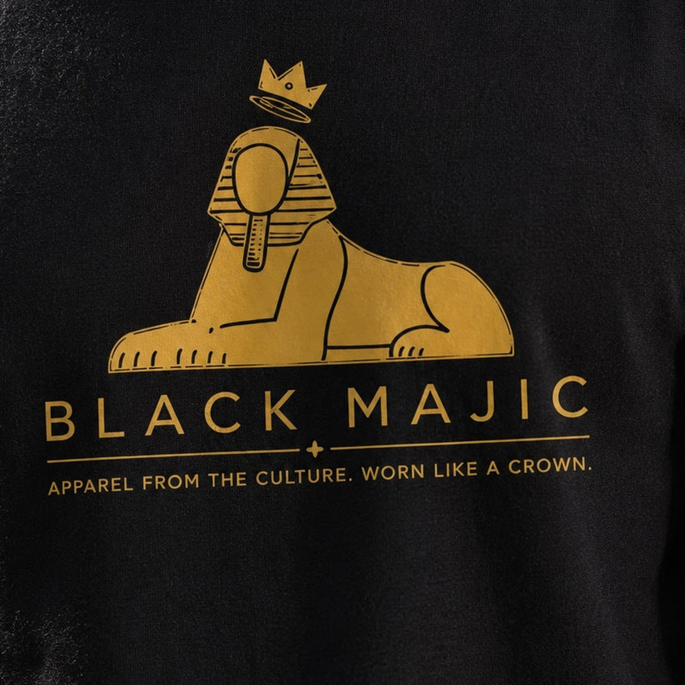 The BLACK MAJIC lockup — filled gold crowned Sphinx over the wordmark and tagline, printed on the Kids Crown Graphic Tee