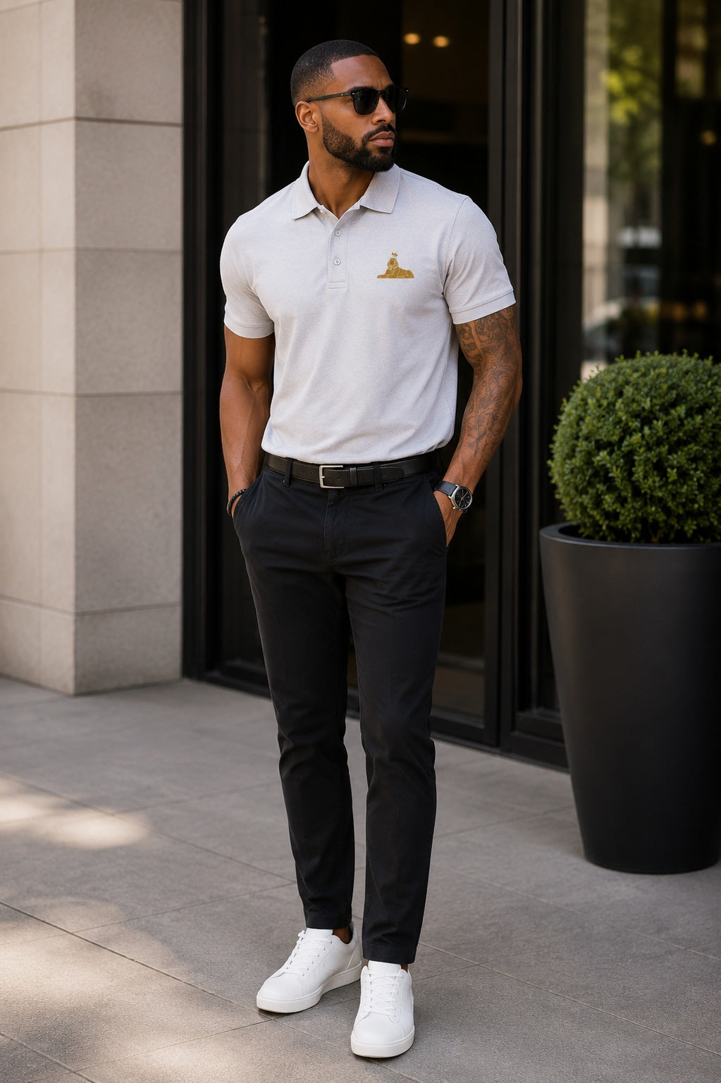 Black man wearing the BLACK MAJIC Adult Crown Polo in White, gold embroidered crowned Sphinx at the left chest