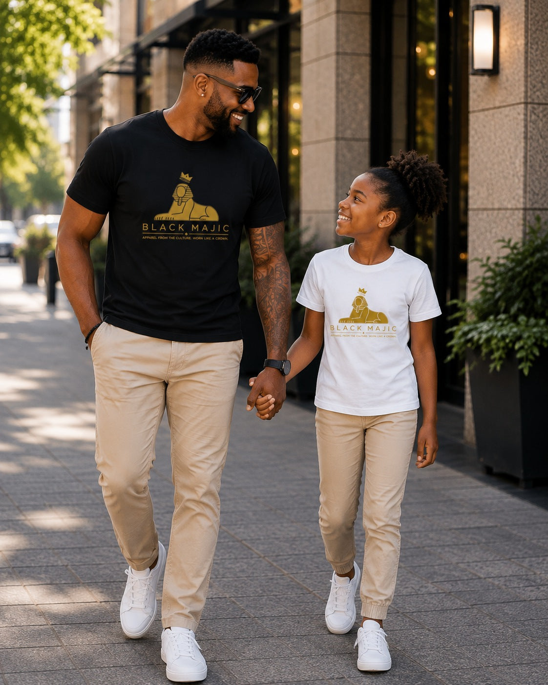 Girl in the white BLACK MAJIC Kids Crown Graphic Tee walking with her father in the black tee