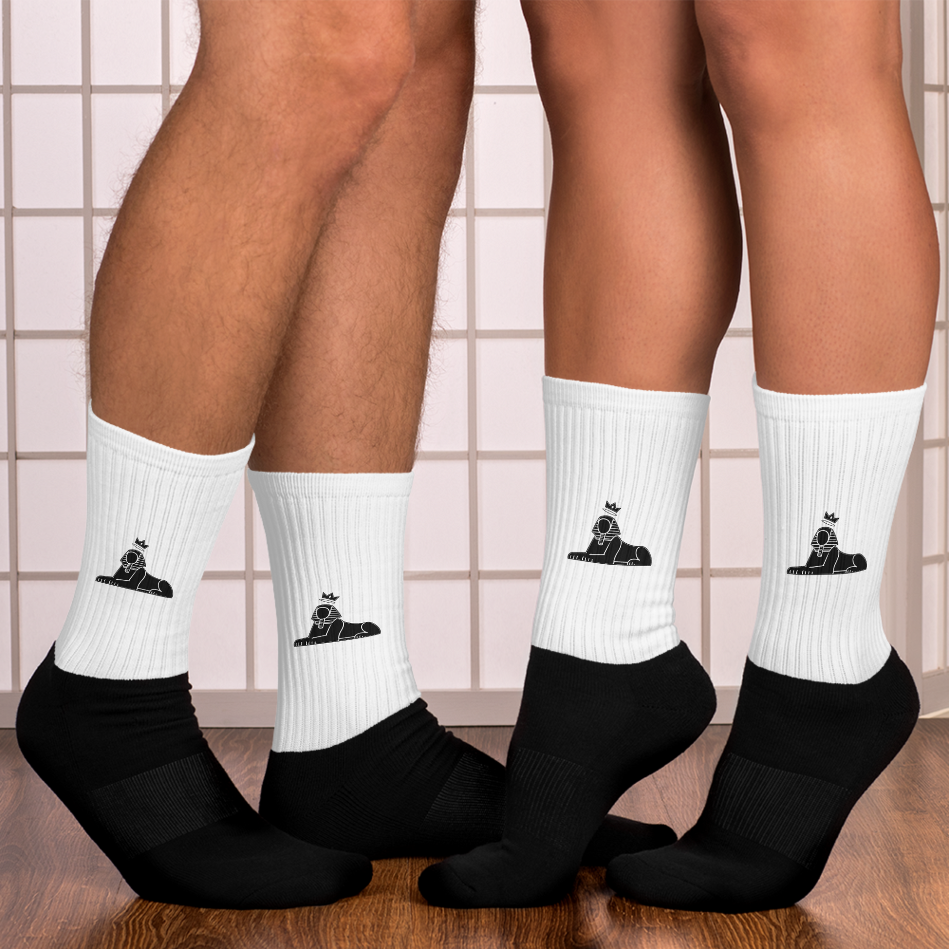 Two people wearing BLACK MAJIC Crown Socks in white against a tiled wall