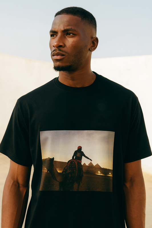 Black man in the Velvet Ritual Pyramid Rider Tee, bright daylight